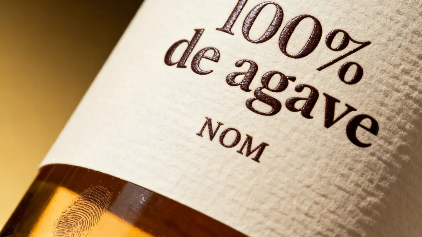 Крупный план этикетки текилы с надписью «100% de agave» и NOM-номером